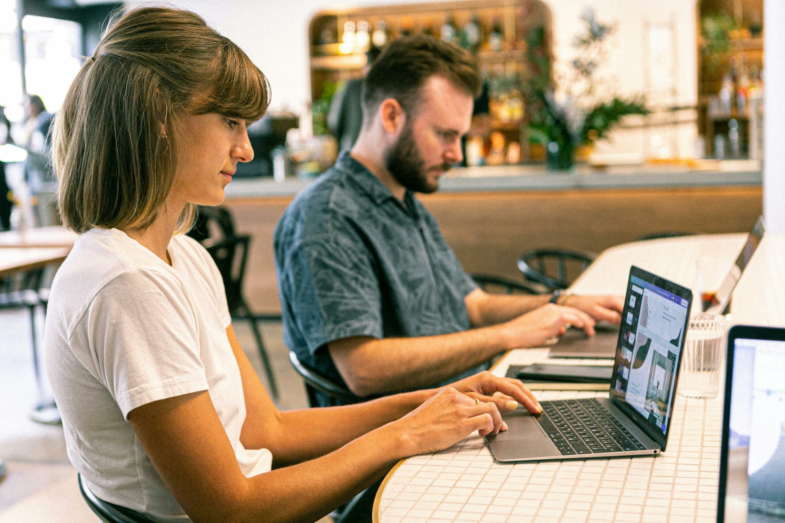 Two people typing on a laptop