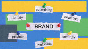 Conceptual image showing key components of branding—identity, advertising, objective, product, strategy, and marketing—pinned around the central word "BRAND" on a colorful background.