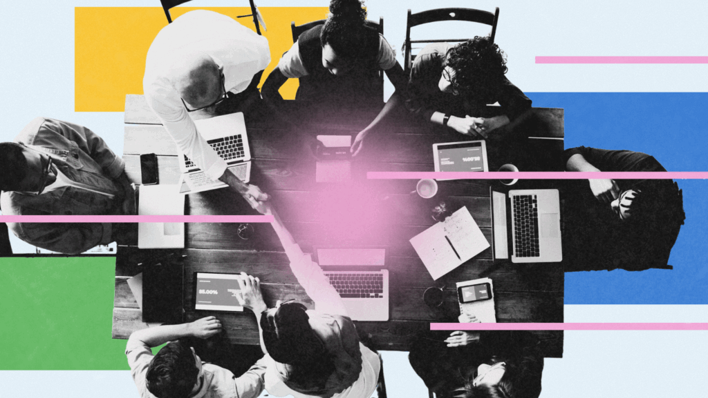 A top-down view of a diverse group of people collaborating at a wooden table with laptops, tablets, and notebooks. Two individuals are shaking hands in the center. The image is overlaid with colorful geometric shapes in blue, yellow, green, and pink for a modern, creative aesthetic.
