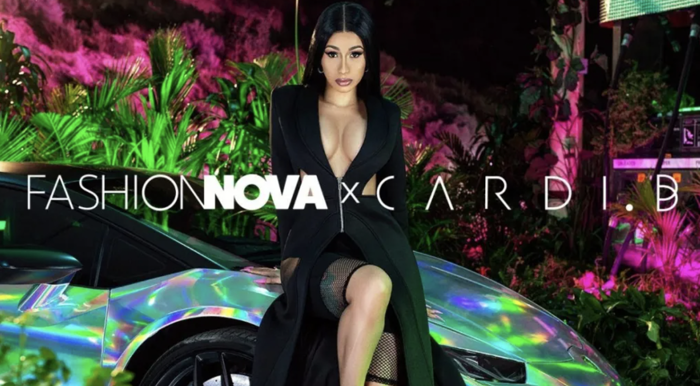 Cardi B poses in a sleek black outfit with a deep neckline, sitting on the hood of a holographic luxury sports car. Behind her is a vibrant backdrop of neon green and pink tropical plants. The promotional banner text across the image reads “FASHION NOVA x CARDI B,” showcasing their fashion collaboration in a bold, glamorous campaign setting.