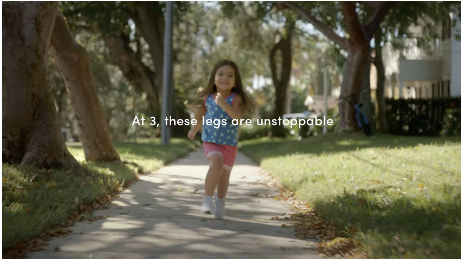 A young girl with brown hair runs joyfully on a sunlit sidewalk, surrounded by grass and trees. Text on the image reads: At 3, these legs are unstoppable—much like curiosity when asking, What is Digital Marketing?.