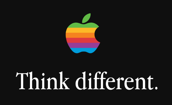Apple's retro rainbow logo above the famous slogan 'Think different.' on a black background, illustrating one of the most iconic and influential brand slogans in marketing history.