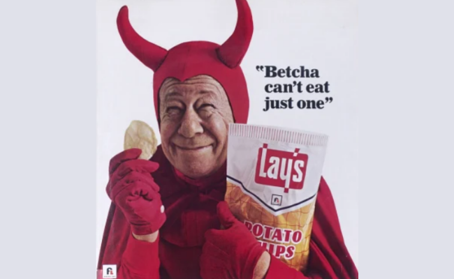 Vintage Lay’s potato chips ad featuring a smiling man in a red devil costume holding a chip and a bag of Lay’s, next to the iconic slogan 'Betcha can’t eat just one.'