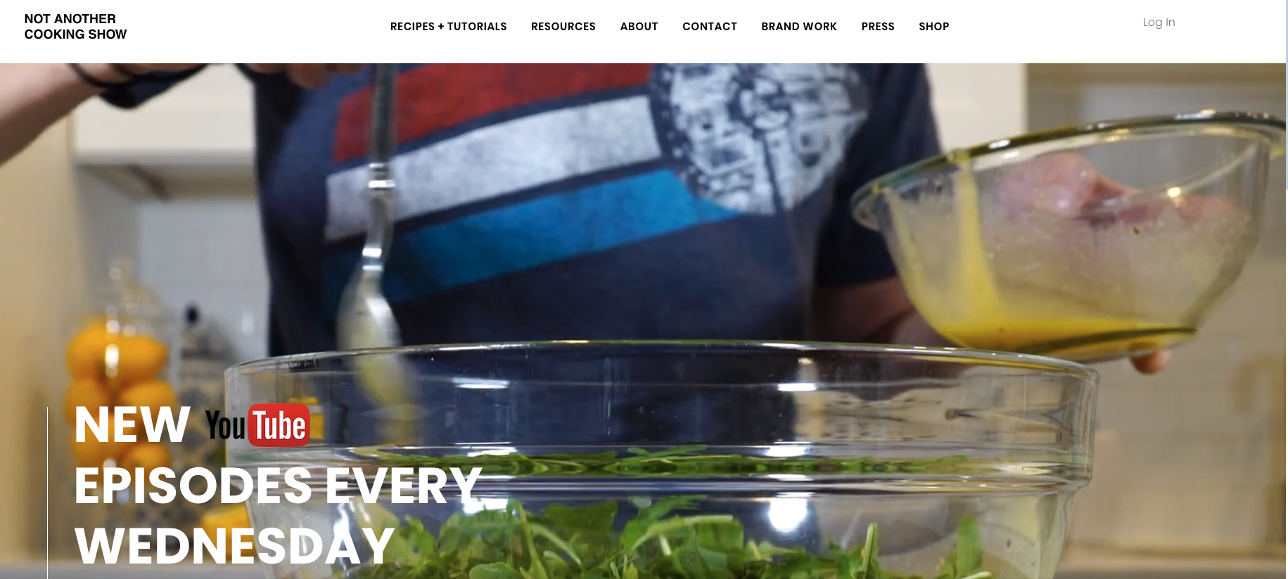 Homepage of Not Another Cooking Show featuring a close-up of salad preparation and bold overlay text promoting new YouTube episodes every Wednesday.