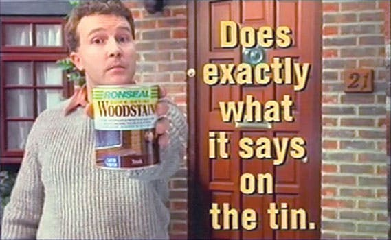 Man holding a can of wood stain beside bold text reading 'Does exactly what it says on the tin,' showcasing a no-nonsense and brutally honest famous slogan.
