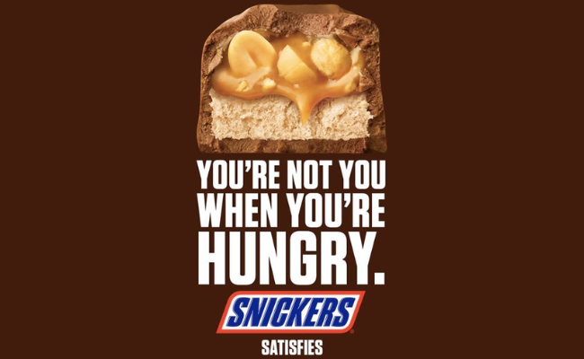 Snickers bar image with caramel and peanuts visible above the slogan 'You’re not you when you’re hungry,' highlighting a humorous and widely recognized famous slogan.