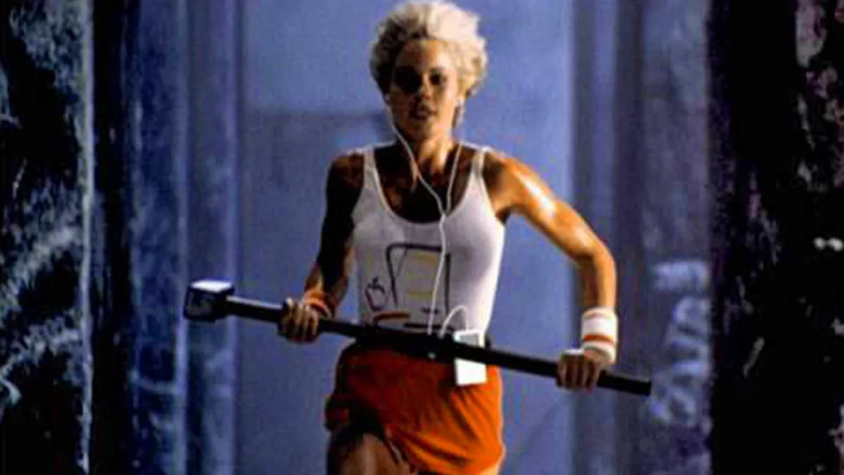 Scene from Apple’s “1984” Super Bowl commercial showing a female athlete running with a sledgehammer toward a screen, symbolizing the launch of the Macintosh.