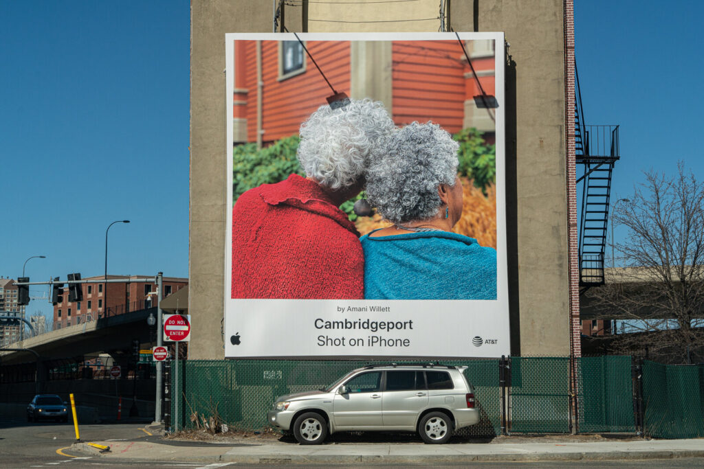 A large billboard featuring real user photography from Apple’s “Shot on iPhone” campaign in an urban setting.