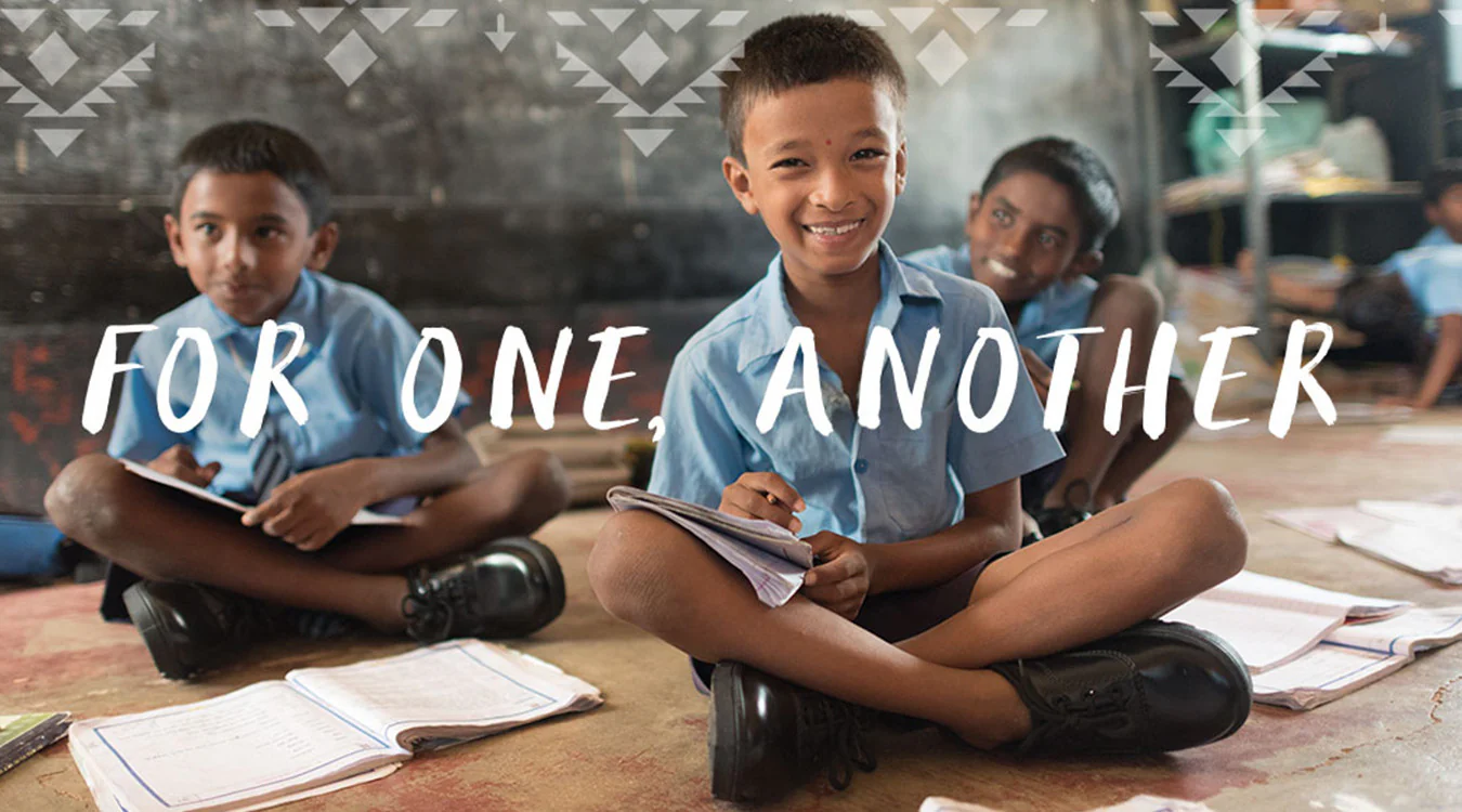 Smiling children wearing school uniforms and TOMS shoes, representing the “One for One” giving model.