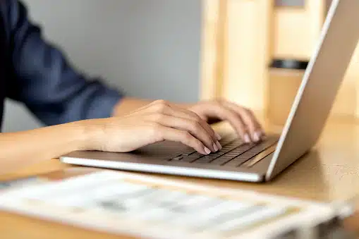 Close-up of a person typing on a laptop at a desk, representing guest blogging or content creation.