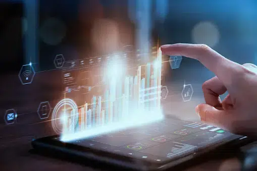 Hand interacting with a tablet displaying holographic bar charts and data visualizations, representing measuring success in user journey mapping.