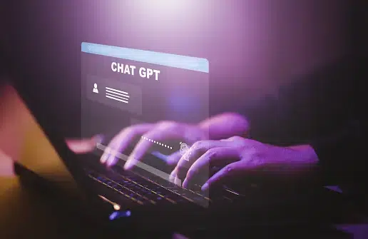 Hands typing on a laptop keyboard with a glowing virtual interface labeled "Chat GPT" floating above the screen.