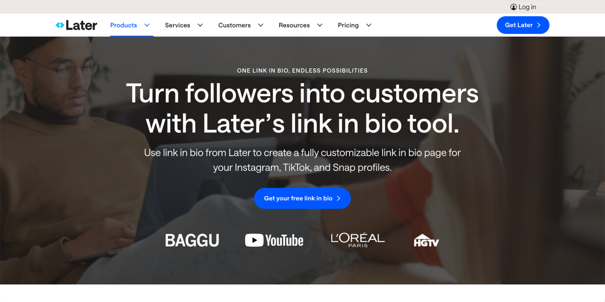 A person sits on a couch using a laptop. The screen displays Later’s website, highlighting its link in bio tool as one of the top Linktree Alternatives. Logos for BAGGU, YouTube, L'Oréal, and HGTV are shown.