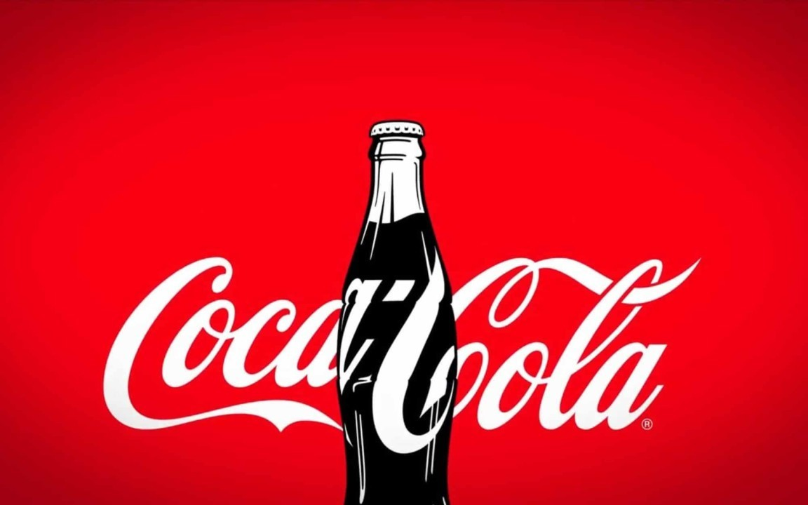 A classic Coca-Cola glass bottle is centered in front of the white Coca-Cola script logo on a bright red background.